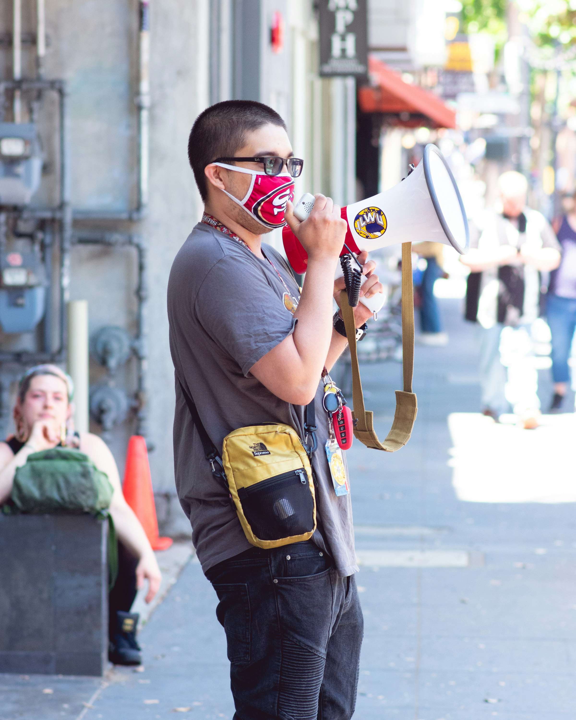 man in gray sweater wearing white mask and black backpack holding black and white camera